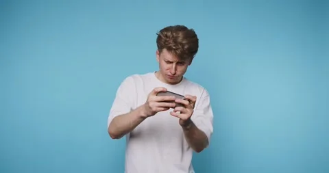 Young man appears intently focused on his mobile gaming, reflecting concent.. Stock Footage 313280650