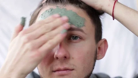A young man applying a clay mask on his face Stock Footage 82401894