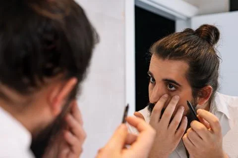 Young man applying eye make-up in the bathroom. Using eyeliner pencil Stock Photos
