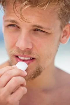 Young man applying moisturizer on his lips Stock Photos