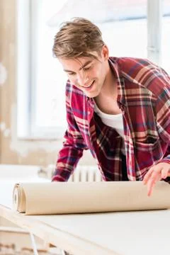 Young man applying paste to the surface of a wallpaper sheet dur 스톡 사진