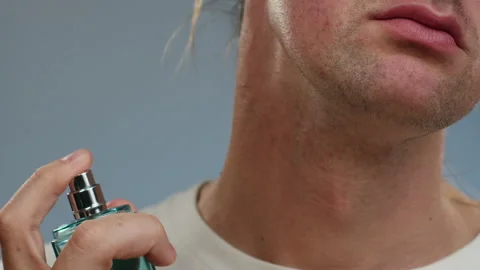 Young man applying perfume on his neck skin close-up, spraying a fragrance 動画素材 281665684