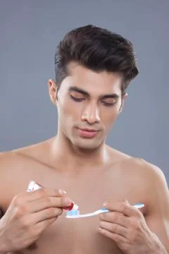 Young man applying toothpaste on toothbrush Stock Photos