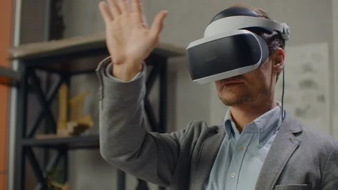 Young man architect in office in virtual reality helmet with hands commits Stock Footage 121801886