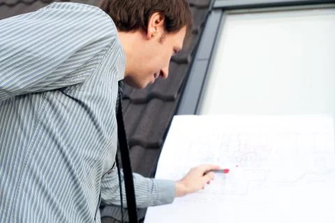 Young man architect presenting a project against the background of the roof a Stock Photos