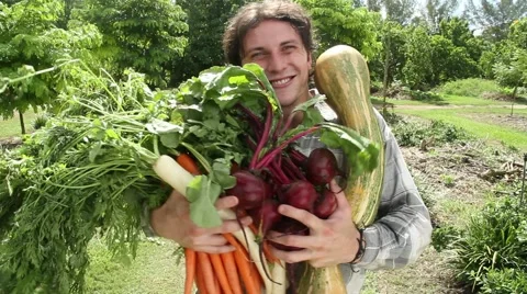 Young man with arms full of fresh vegetables turns and smiles to camera Stock Footage 45523932