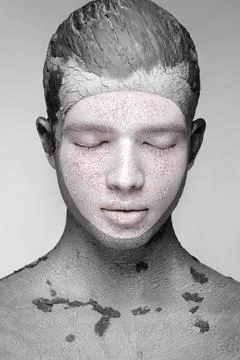 Young man with art creative make-up with mud on his face. Cosmetic mask. Stock Photos