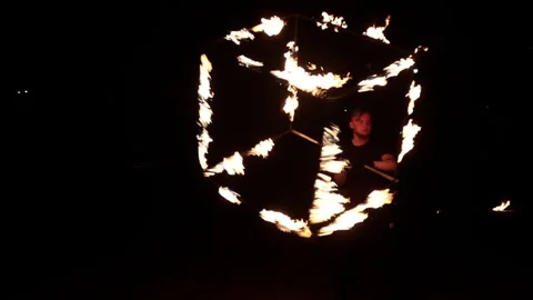 A young man, an artist, performs with a fiery metal cube. Stock Footage 246219359