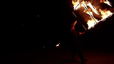 A young man, an artist, performs with a fiery metal cube. Stock Footage 246222382