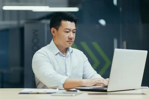 A young man of Asian origin programmer, developer works in the office at a Stock Photos