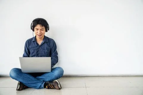 Young man asian using computer laptop smiling and listening nice music Stock-Fotos