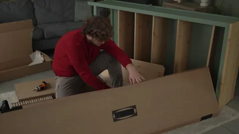 Young man assembling new wooden furniture in living room Video stock 332430851
