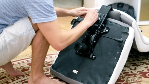 A young man is assembling an office chair. The concept of repair and assembly of Stock Footage 107839741