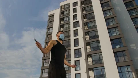 A young man of athletic build jumps on a skipping rope in a medical mask. Video stock 140104472