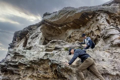 Young man attempting to help another (motion blur) climb Fotos de archivo