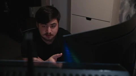 Young man attentively looking at computer screen in dark room Stock Footage 323438259