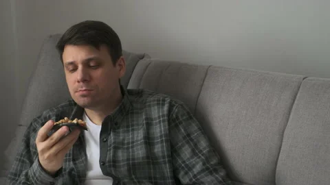 Young man bachelor sitting on sofa at home and eating tasty pizza from delivery. Stock Footage 153702972