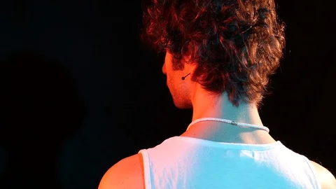 Young man from the back dressed dressed in a white tank top moves his head down  Stock Footage 126855626