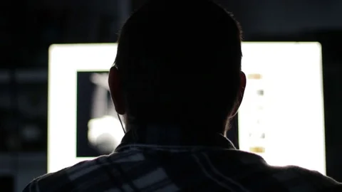 Young Man Back light Looks At Computer Display with Internet Browser Stock Footage