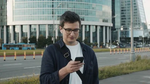 Young man on background of business centre building texting on a phone 動画素材 137313728