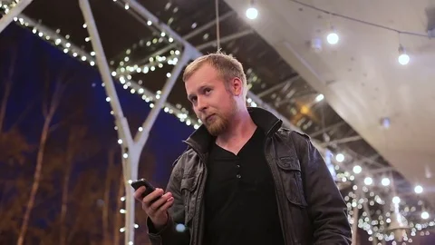 The young man in the background of the city at night talking on the phone Stock Footage 75045513