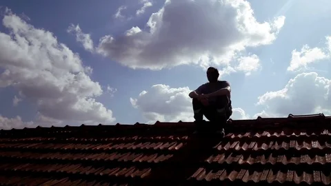 Young Man Backlight sits on top of roof thinking Stock Footage 74120989
