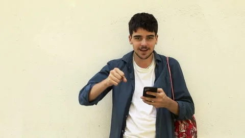 Young man with backpack and mobile phone celebrating success Stock Footage 254014937