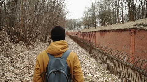 A young man With backpack on back walks through the park in the spring or autumn Stock Footage 74110660