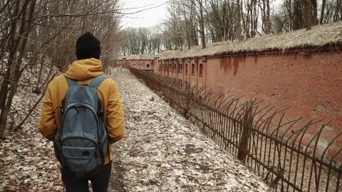 A young man With backpack on back walks through the park in the spring or autumn Stock Footage 74124807