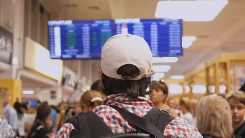 Young man with backpack checking flight information on digital schedule display Stock Footage 125741277