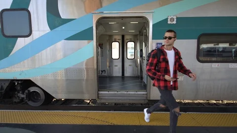 Young man with backpack get off train on platform of railway station Los Angeles Stock Footage 99070727
