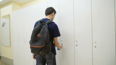 A young man with a backpack on his back opens the closet in the locker room Video stock 98123685