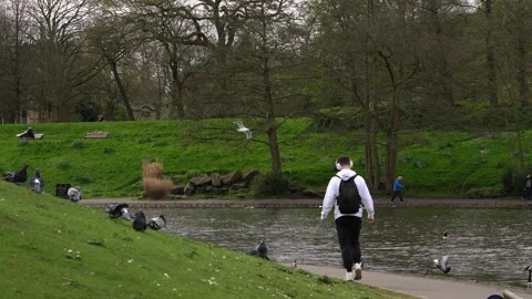 A young man with a backpack on his back and headphones on his head walks calmly Stock Footage 304882401
