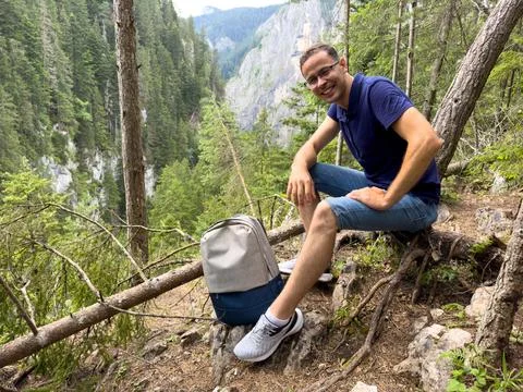Young man with backpack resting in forest in mountains Stock Photos