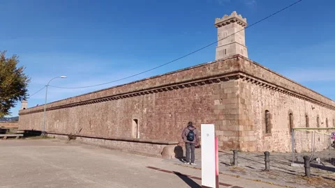 Young man with a backpack resting on the historic walls of the Montjuic Castle Stock-Footage 328173317