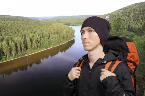 Young man with a backpack stands in front of a river Stock Photos