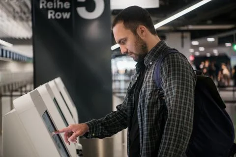 Young man with backpack touching interactive display using self service machine Stock Photos