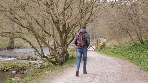 Young man with backpack walking in the mountain forest near to mountain river. Stock Footage 106776741