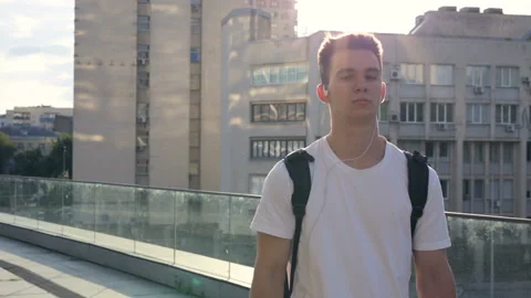 Young man with backpack walking at the street and listening to music. Stock Footage 92160697