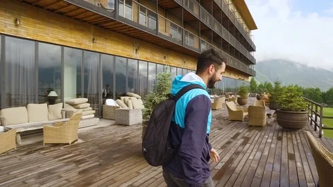 Young man with a backpack walking on the terrace and looking at the mountains Stock Footage 87351522