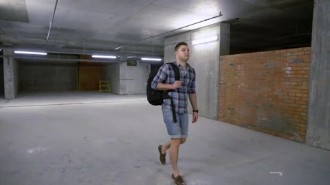 Young man with backpack walking through a basement Stock Footage 132356890