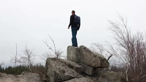 Young man with backpack walking on top of the rock and taking selfie on cel.. Stock Footage 305070391