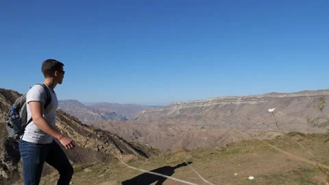 Young man with a backpack walks down the slope against the background of Video stock 146943307