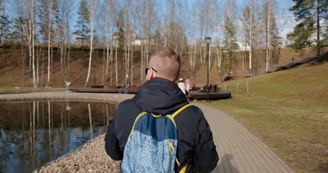 A young man with a backpack walks through the spring park Stock Footage 274092129