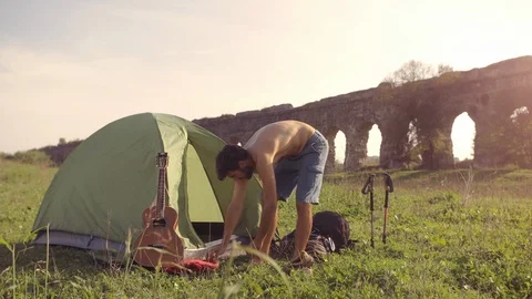 Young man backpacker dressing wearing t-shirt outside camping tent sitting on Stock-Footage 91078672