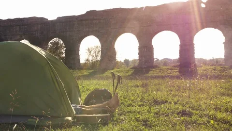 Young man backpacker sleeping in camping tent on grass with feet outside in Stock Footage 86267004