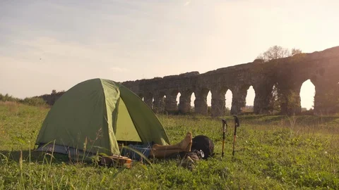 Young man backpacker sleeping in camping tent on grass with feet outside in Stock Footage 91076737