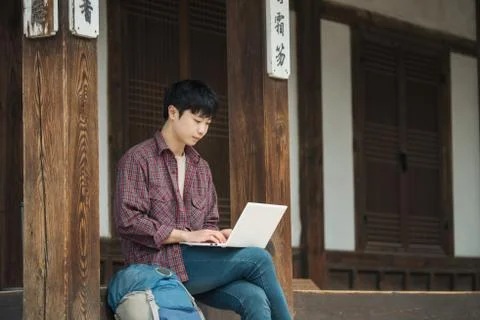 A young man backpacking in Korea. using a laptop sitting in a Korean traditio Stock Photos