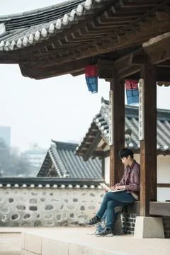 A young man backpacking in Korea. using a laptop sitting in a Korean traditio Stock Photos