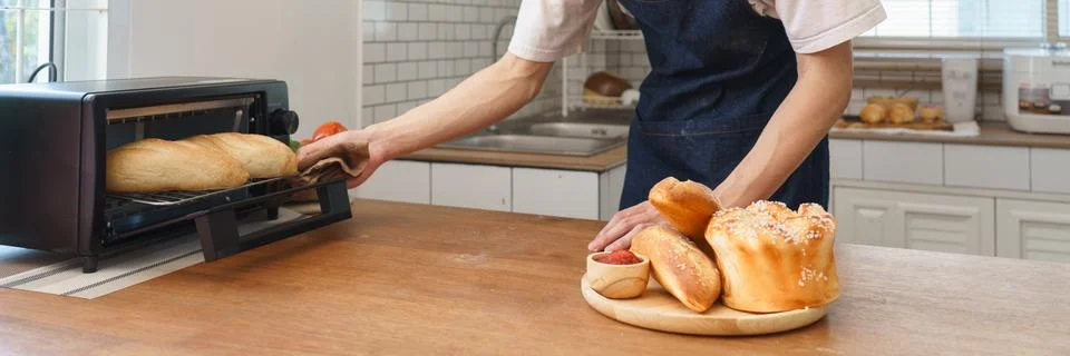 Young man baking bread using small oven in cozy home kitchen with natural w.. Stock Photos